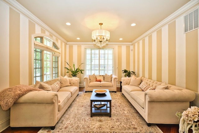 living room featuring plenty of natural light, wood-type flooring, a chandelier, and ornamental molding