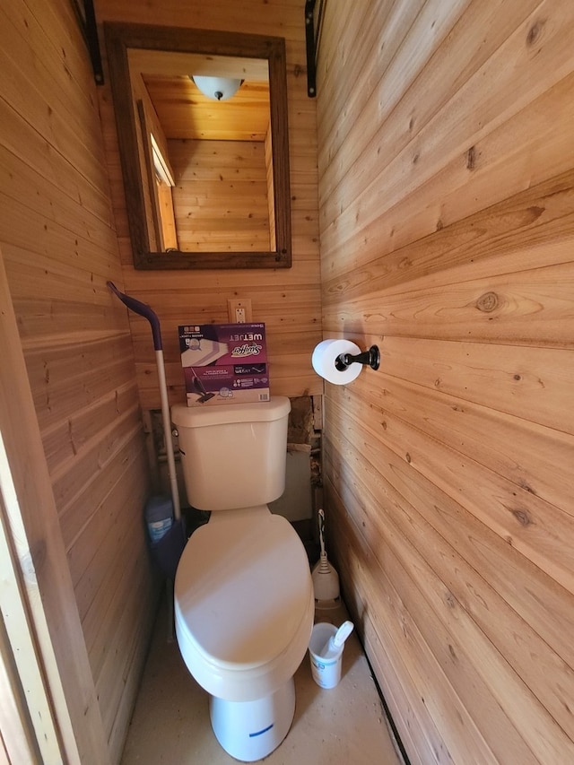 bathroom featuring wood walls and toilet