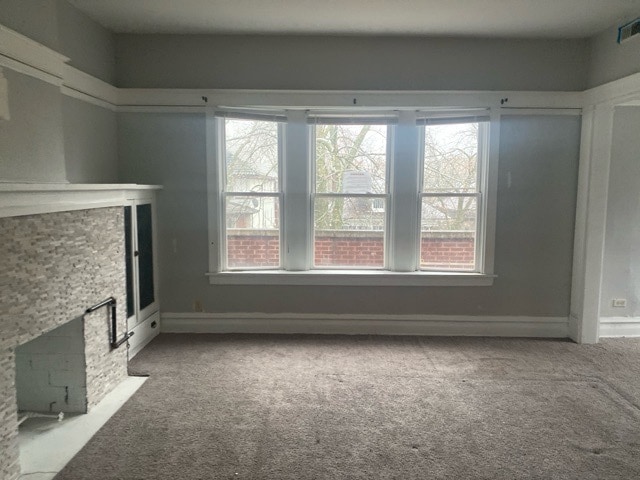 unfurnished living room with a fireplace and carpet