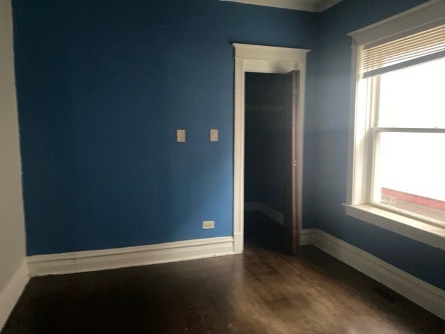 empty room with a healthy amount of sunlight and dark hardwood / wood-style floors