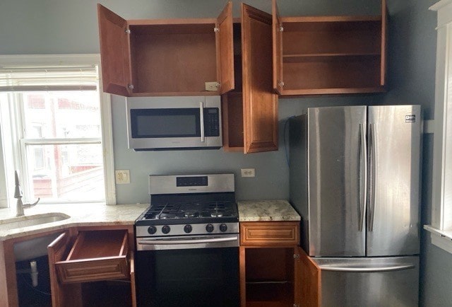 kitchen featuring sink, stainless steel appliances, and light stone counters