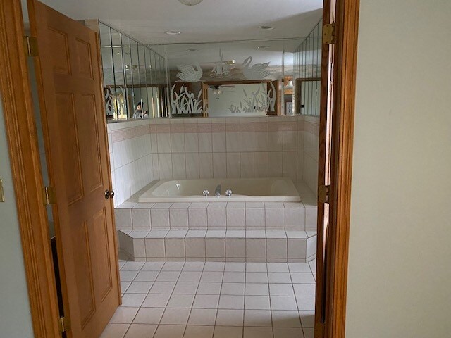 bathroom with tiled bath and tile patterned floors