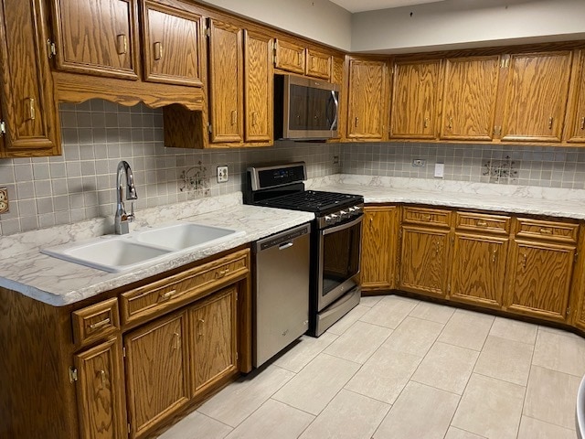 kitchen featuring sink, appliances with stainless steel finishes, backsplash, and light tile patterned floors