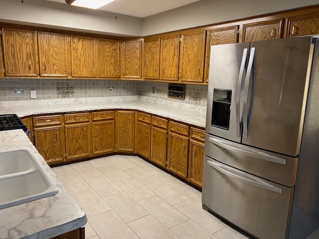 kitchen with sink, light tile patterned flooring, stainless steel refrigerator with ice dispenser, and tasteful backsplash