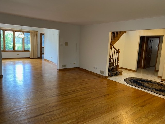 unfurnished living room featuring light hardwood / wood-style flooring and an inviting chandelier