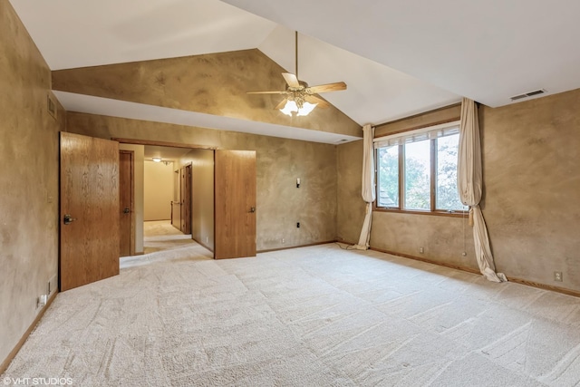 empty room featuring vaulted ceiling, light colored carpet, and ceiling fan