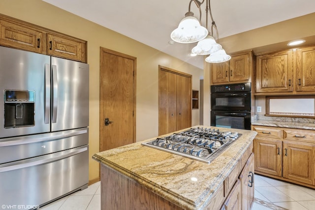 kitchen featuring a kitchen island, light tile patterned flooring, appliances with stainless steel finishes, and light stone counters