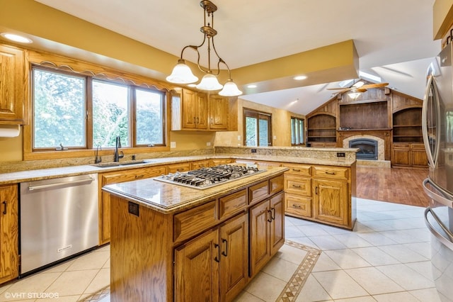 kitchen featuring sink, decorative light fixtures, vaulted ceiling, a kitchen island, and stainless steel appliances