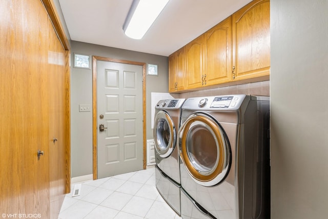 laundry room with cabinets, light tile patterned floors, and washer and clothes dryer