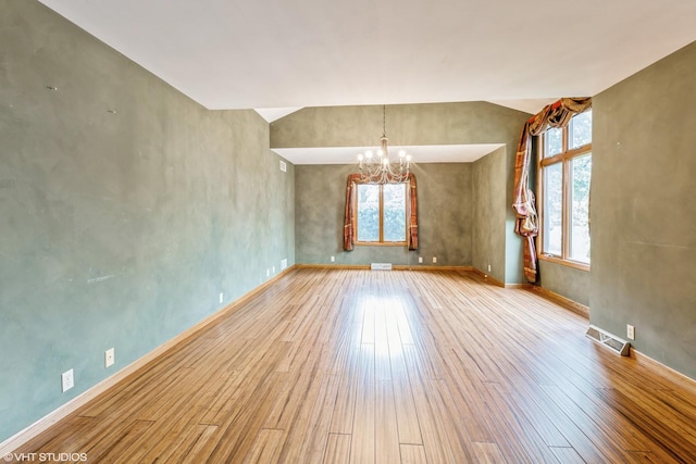 empty room featuring vaulted ceiling, an inviting chandelier, and light hardwood / wood-style flooring