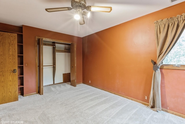 unfurnished bedroom with light carpet, multiple closets, and ceiling fan