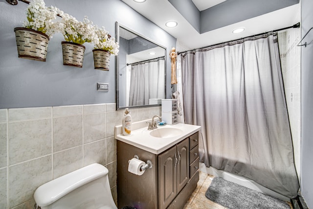 bathroom with tile floors, vanity, toilet, and tile walls