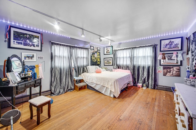 bedroom featuring a baseboard heating unit, track lighting, and light wood-type flooring