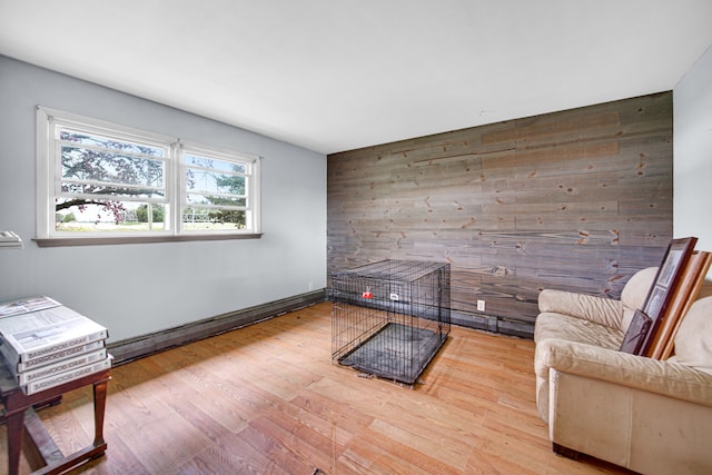 unfurnished room featuring wood-type flooring, wooden walls, and a baseboard heating unit