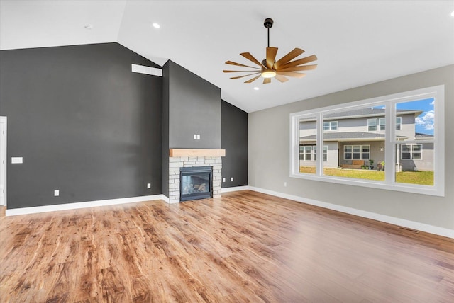 unfurnished living room with ceiling fan, light hardwood / wood-style flooring, a stone fireplace, and lofted ceiling