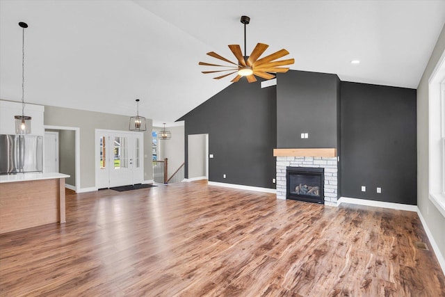 unfurnished living room featuring wood-type flooring, high vaulted ceiling, a fireplace, and ceiling fan