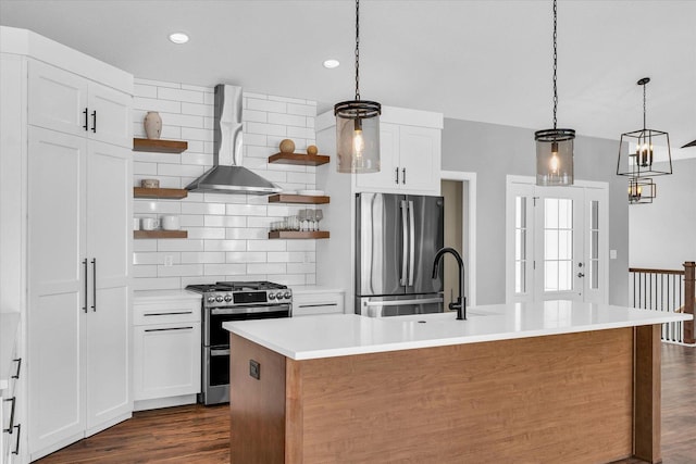 kitchen featuring stainless steel appliances, a center island with sink, white cabinets, and wall chimney exhaust hood