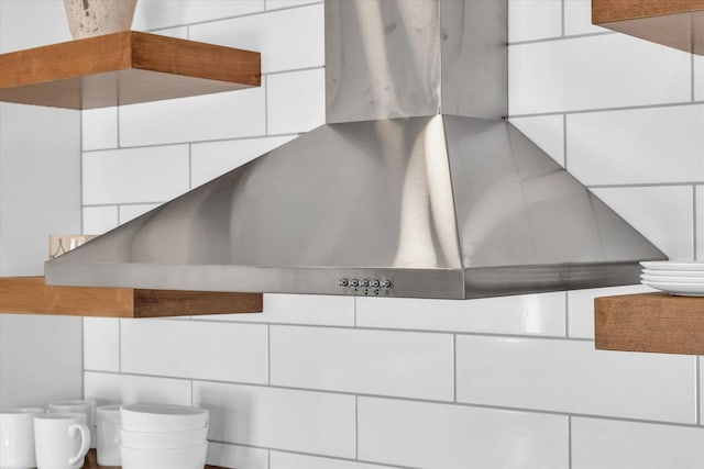 room details with wall chimney range hood and white cabinetry