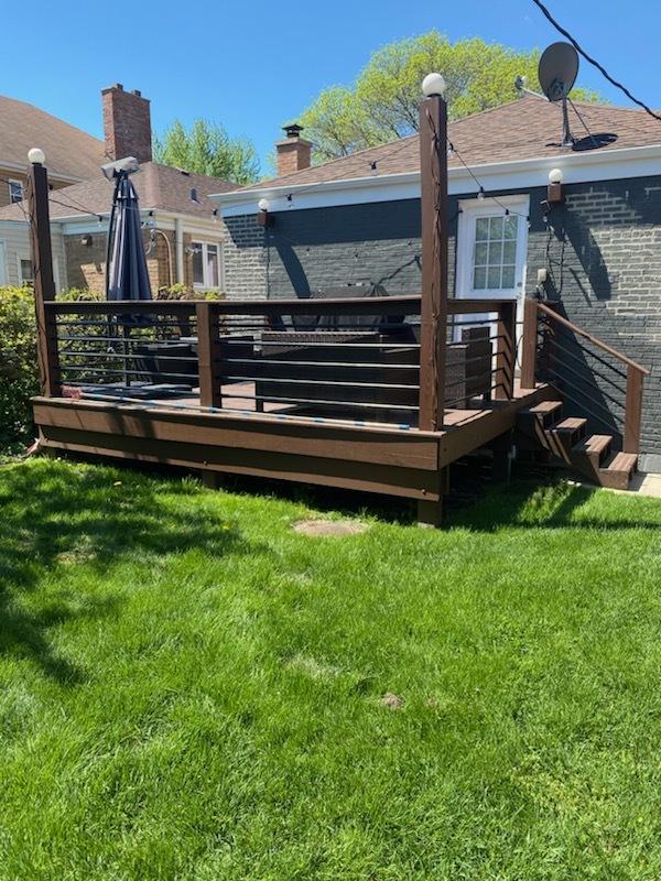 rear view of house featuring a yard and a deck