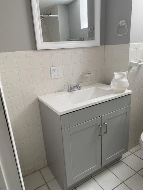 bathroom featuring tile patterned flooring, vanity, tile walls, and toilet