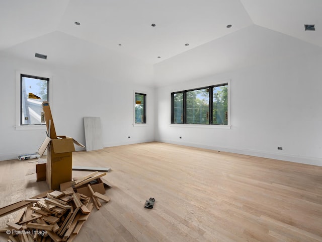 unfurnished living room with a wealth of natural light, light hardwood / wood-style flooring, and vaulted ceiling