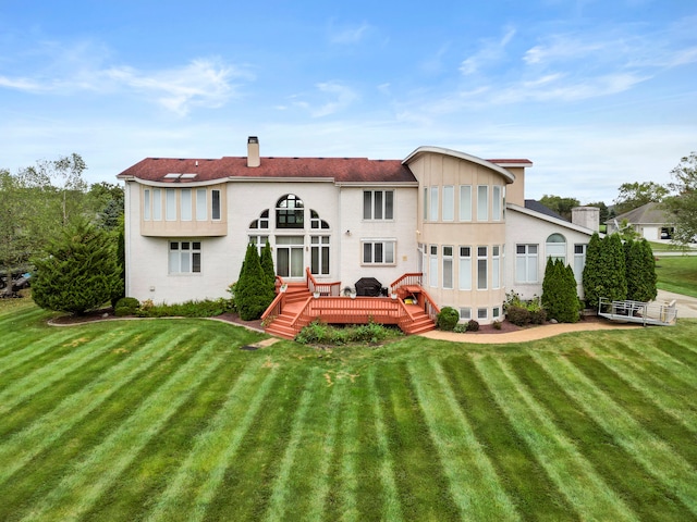 rear view of property featuring a deck and a lawn