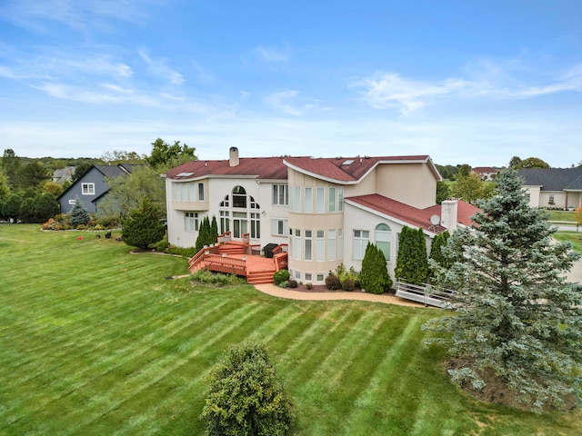 rear view of house featuring a lawn and a deck