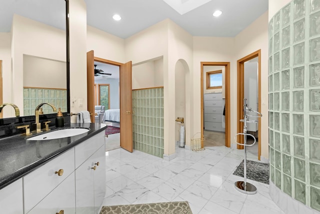 bathroom featuring ceiling fan, vanity, and walk in shower