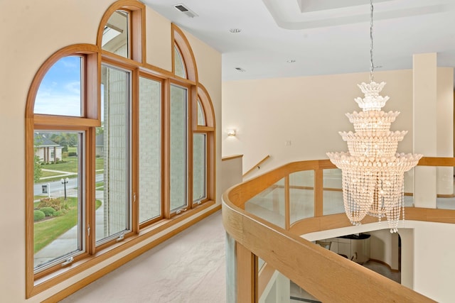 hall featuring an inviting chandelier, a high ceiling, and light carpet