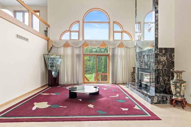 playroom with a high ceiling, a high end fireplace, and tile patterned floors