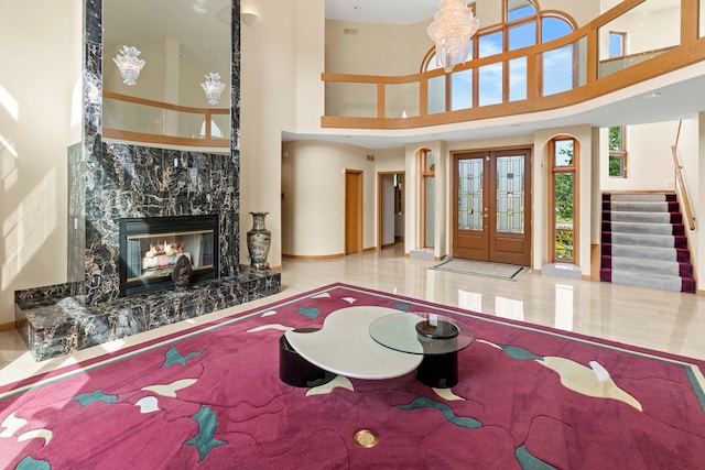 interior space with french doors, a towering ceiling, and a high end fireplace