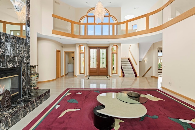 entryway featuring a high ceiling, a fireplace, an inviting chandelier, and french doors