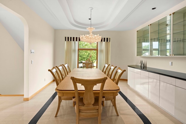 dining room with a notable chandelier, a raised ceiling, and light tile patterned floors