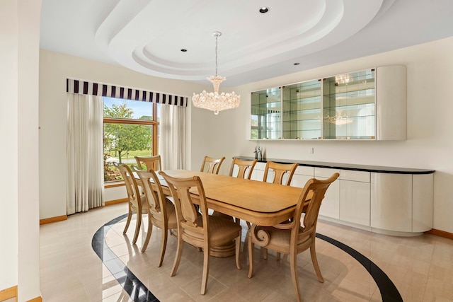 dining space featuring a raised ceiling, an inviting chandelier, and light tile patterned floors