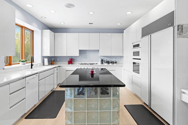 kitchen featuring white cabinets, white appliances, light tile patterned floors, a center island, and sink