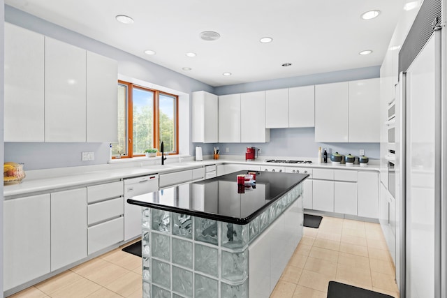 kitchen with white appliances, white cabinetry, a center island, and light tile patterned floors