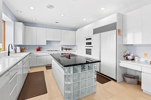 kitchen featuring sink, white cabinetry, white appliances, and a kitchen island