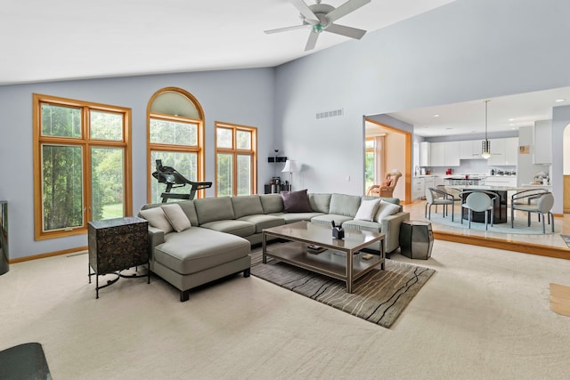 living room with light carpet, ceiling fan, and high vaulted ceiling