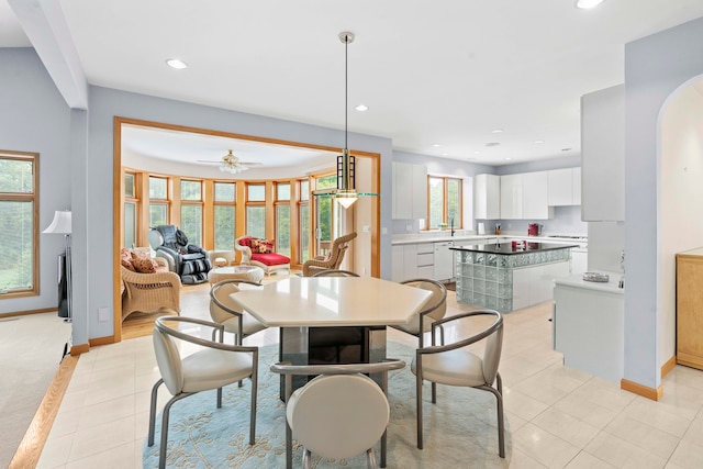 tiled dining room featuring a wealth of natural light, ceiling fan, and sink