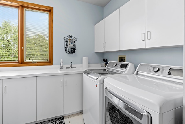 laundry area with light tile patterned floors, sink, independent washer and dryer, and cabinets