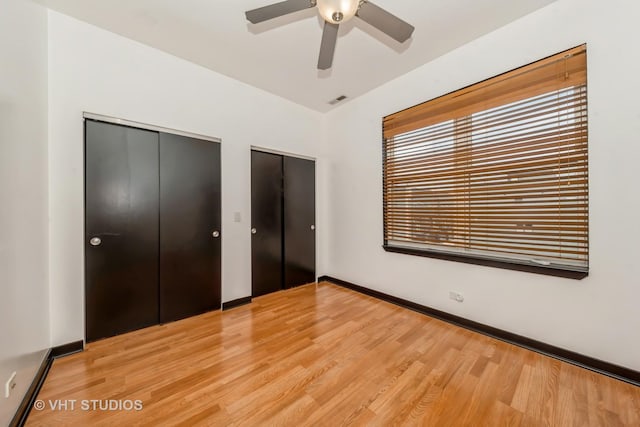 834 E 45th St, Chicago, IL 60653 - unfurnished bedroom featuring light wood finished floors, two closets, a ceiling fan, and baseboards