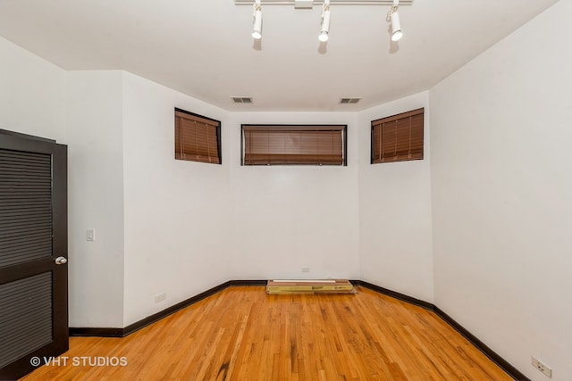 unfurnished room with track lighting and hardwood / wood-style floors