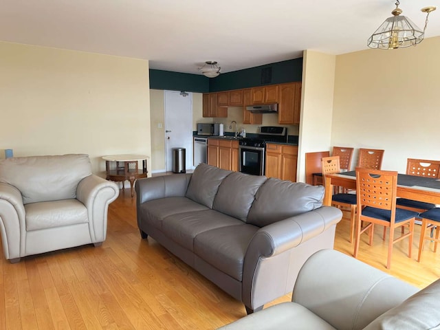 living room featuring sink, light hardwood / wood-style floors, and a notable chandelier