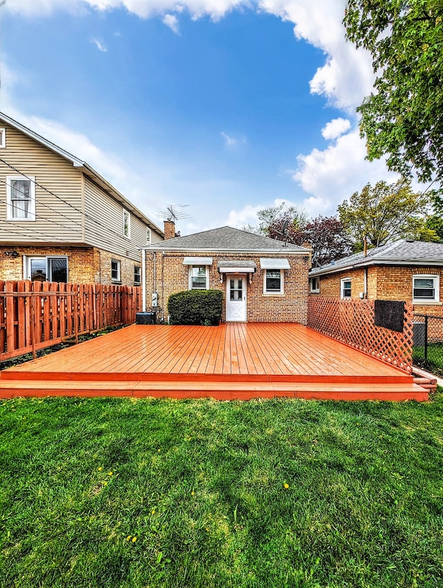 rear view of property with a deck and a lawn