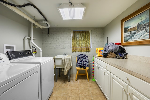 clothes washing area featuring hookup for a washing machine, cabinets, brick wall, light tile flooring, and washer and dryer