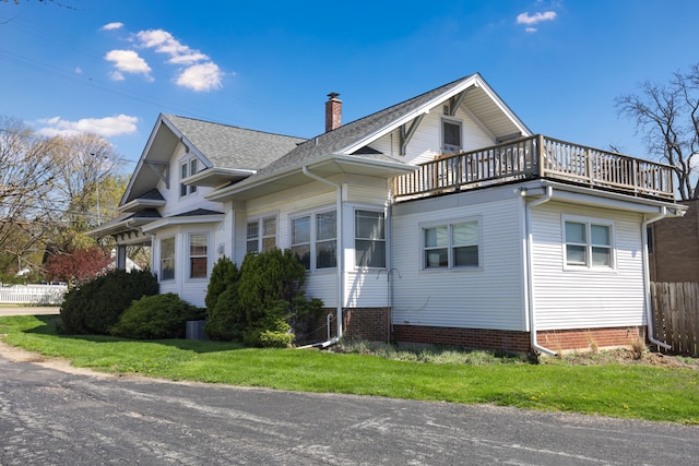 view of front facade featuring central AC, a balcony, and a front lawn