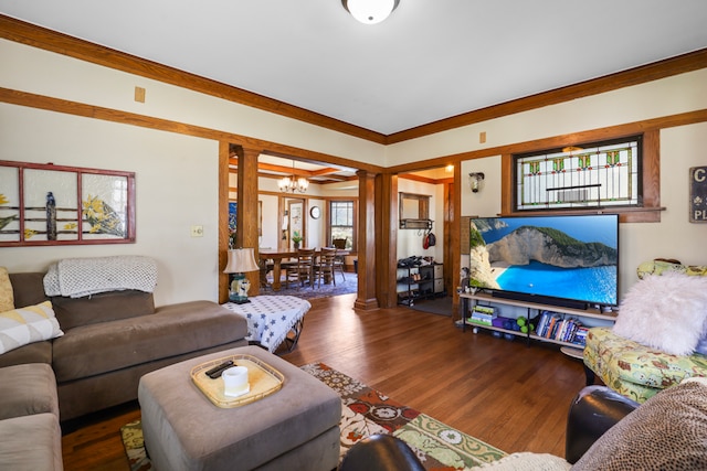 living room featuring a chandelier, crown molding, dark hardwood / wood-style flooring, and ornate columns