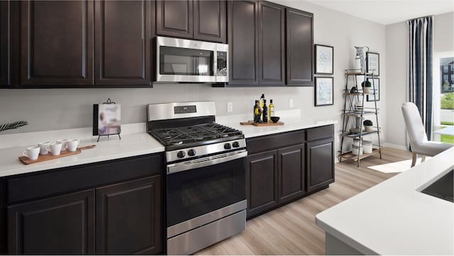 kitchen featuring dark brown cabinets, stainless steel appliances, and light wood-type flooring