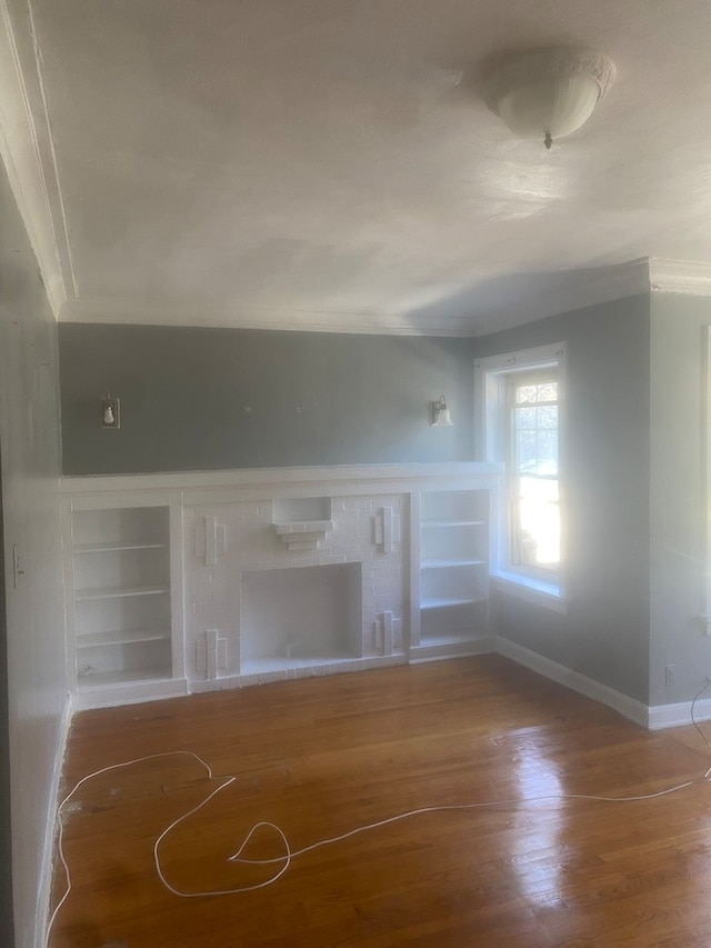 unfurnished living room with built in features, crown molding, and dark wood-type flooring