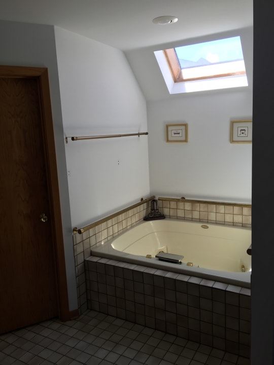 bathroom featuring tile patterned floors, tiled bath, and lofted ceiling with skylight